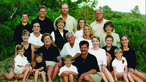 Three generations of the Flegenheimer Family are in the photo, taken outside with natural foliage background. The family is pictured in casual apparel. 